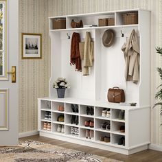 a white coat rack filled with coats and shoes next to a potted plant on top of a rug