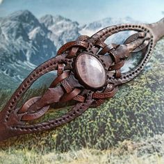 a wooden brooch sitting on top of a piece of leather