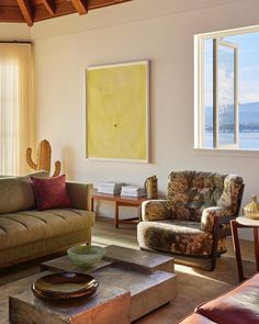 a living room filled with furniture and a large painting hanging on the wall above it