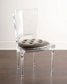 a clear chair sitting on top of a hard wood floor next to a white wall