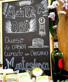 a blackboard sign sitting on top of a table next to some vegetables and cheese