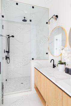 a bathroom with two sinks, mirrors and a walk - in shower next to it