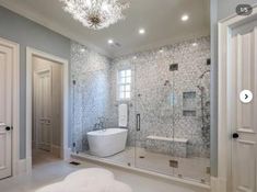 a bathroom with a tub, shower and chandelier hanging from the ceiling in it