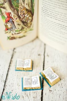 an open book sitting on top of a wooden table next to small pieces of paper