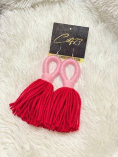 two pairs of pink scissors with red tassels on a white furnishing