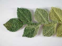 four knitted leaves on a white surface