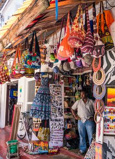 a man standing in front of a store filled with colorful items