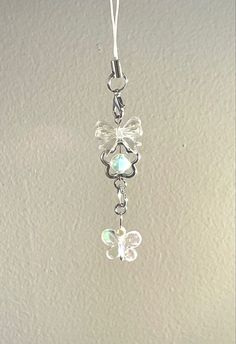 a glass angel ornament hanging from a white wall with a string attached to it