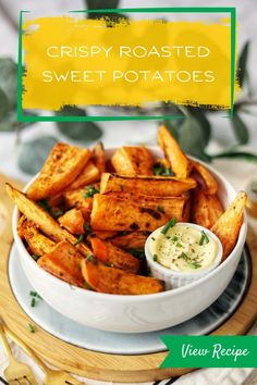 crispy roasted sweet potatoes in a white bowl with ranch dressing on the side and text overlay that reads, crispy roasted sweet potatoes