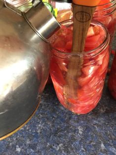 jars filled with sliced tomatoes sit on a counter next to a tea kettle and oranges