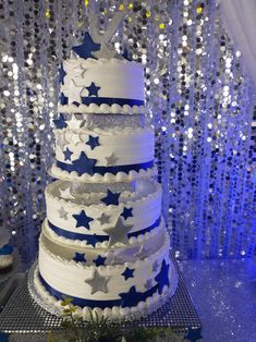 a white and blue wedding cake with stars on the top is surrounded by sequins