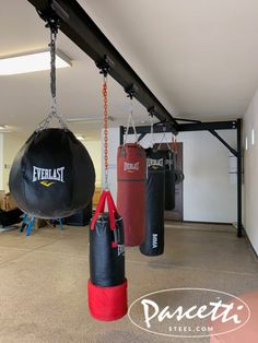 there are two boxing bags hanging from the ceiling in this room with other punching gear