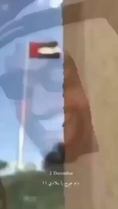 the reflection of a man's face in a window with a flag on it