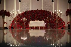 a white bench surrounded by red flowers and candles