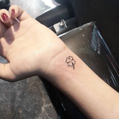 a small four leaf clover tattoo on the wrist