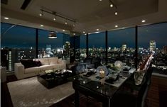 a living room filled with furniture and large windows overlooking the city lights at night time