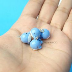 three tiny blue elephants sitting on top of a persons hand in front of a blue background