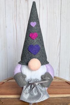 a small gnome with hearts on his head sitting on top of a piece of wood