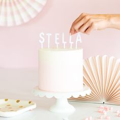 a person holding a cake with the word stella written on it in white frosting