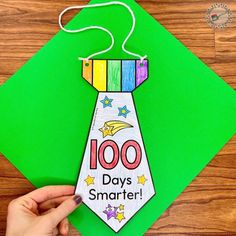 a hand holding a paper tie with the words 100 days smarter on it and stars