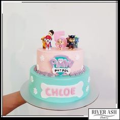 a hand holding up a cake decorated with cartoon characters and the words'paw patrol '