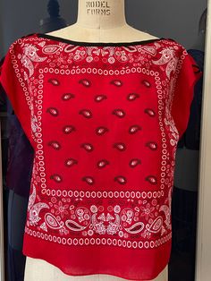 a mannequin wearing a red top with paisley designs on it's shoulders