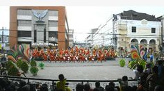 a group of people that are standing in the street with some kind of parade behind them