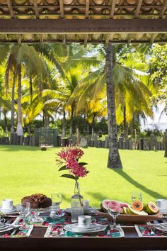 the table is set with fruit and watermelon for two people to eat on