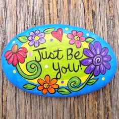 a painted rock that says, just be you with flowers and hearts on the side