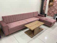 a living room with a pink couch and coffee table in the middle, next to a brick wall