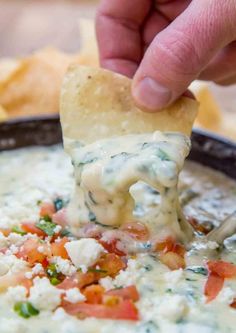 a hand dipping a tortilla chip into a bowl of quesadilla dip