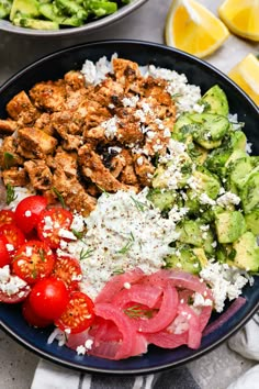 a bowl filled with meat, vegetables and feta cheese on top of a table