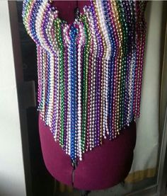 a mannequin with beads on it and a purple dress behind the mannequin