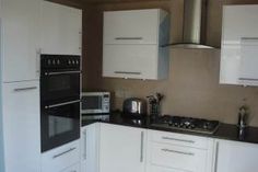 a kitchen with white cabinets, black counter tops and stainless steel stove top ovens