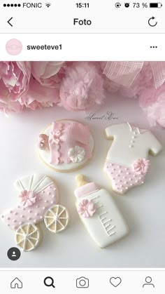 some cookies that are on a table with pink flowers and baby items in the background