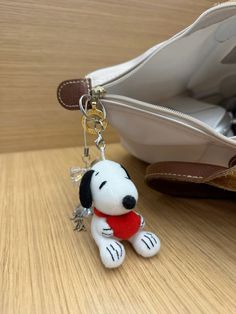 a small keychain with a dog on it sitting next to an open purse