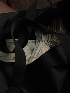 a black bag filled with money sitting on top of a wooden floor