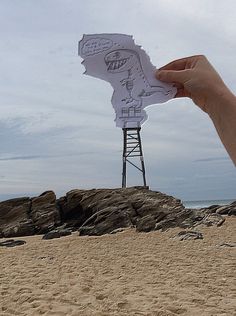 a person holding up a piece of paper with a drawing on it