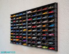 there are many toy cars on display in this wall - to - ceiling storage unit