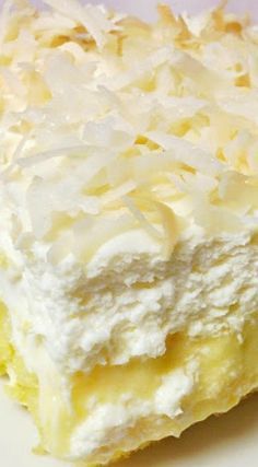 a piece of cake with white frosting and coconut on top