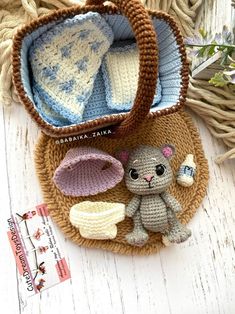 a small crocheted basket with two stuffed animals in it and some baby items