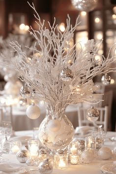 a vase filled with white ornaments on top of a table covered in candles and lights