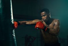 a young man wearing red boxing gloves is in the ring with a punching glove on his shoulder