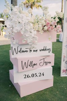 three pink boxes with white flowers are stacked on top of each other in the grass