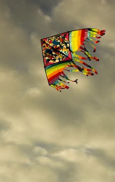 a colorful kite is flying in the cloudy sky