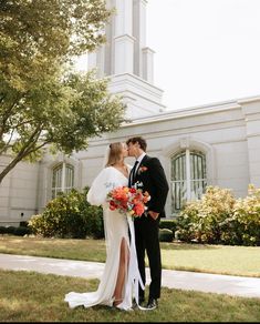 a bride and groom kissing in front of a large white building with a steeple