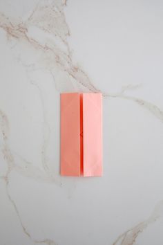 an orange piece of paper sitting on top of a white marble counter next to a knife