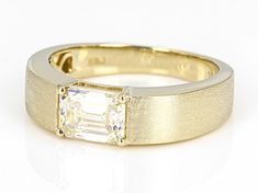 a yellow gold ring with an emerald cut diamond in the center, on a white background