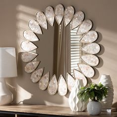 a mirror sitting on top of a wooden table next to a vase with a plant