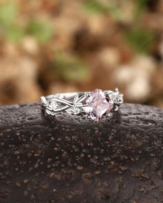 a pink diamond ring sitting on top of a rock